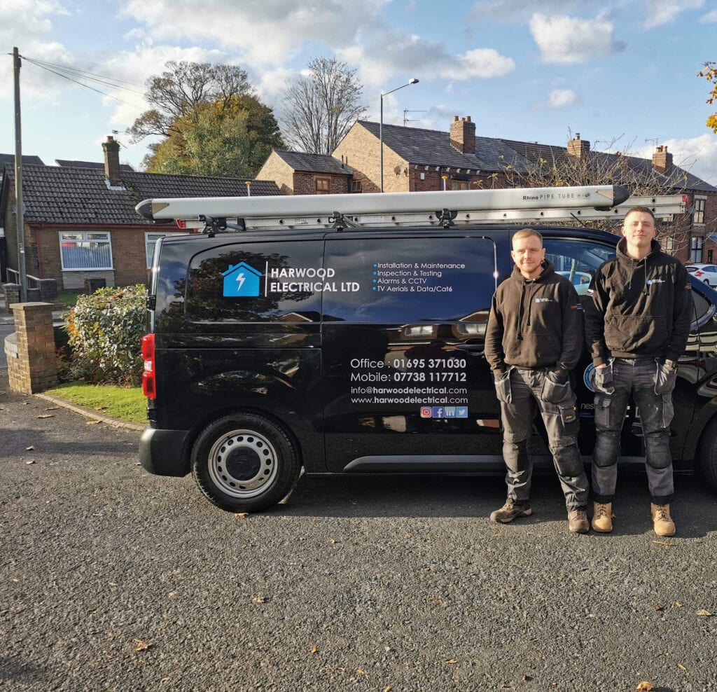 The Harwood Electrical team standing beside their van in Wigan